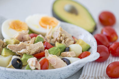 A salad with tuna, avocado, cherry tomatoes, olives and hard-boiled eggs.