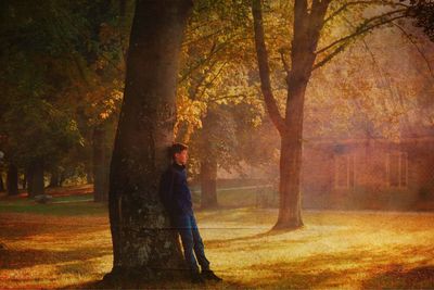 Woman standing by tree in forest during autumn