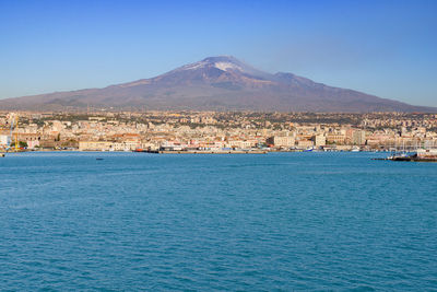 Scenic view of sea and buildings against clear blue sky