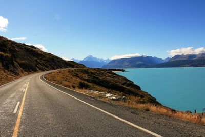 Empty road by lake pukaki against sky