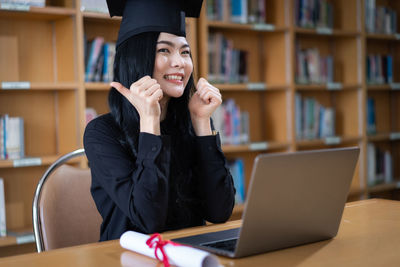 Young student gesturing while sitting at library