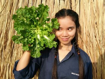 Smiling young woman holding leaf vegetable