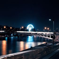 Illuminated bridge over river at night