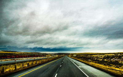 Empty road against cloudy sky