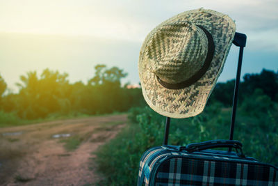 Close-up of sun hat on luggage at field