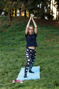 The relaxed girl is doing yoga in the park on carpet