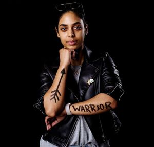 Portrait of woman with tattoos standing against black background