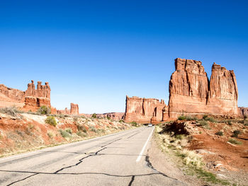 Rock formations on road against blue sky