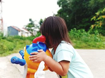 Side view of woman holding toy against plants