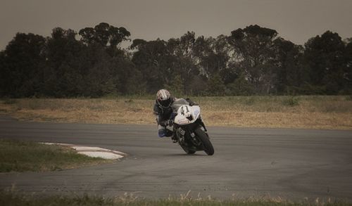 Rear view of people riding motorcycle on road against trees