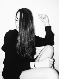 Rear view of woman sitting against white background