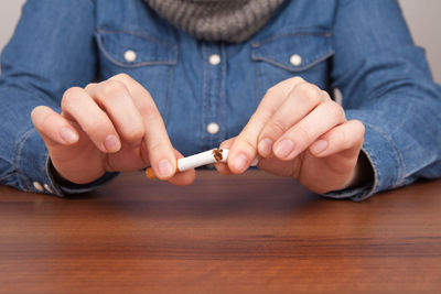 Midsection of woman breaking cigarette at table