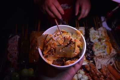 Cropped hand holding food in bowl at market stall