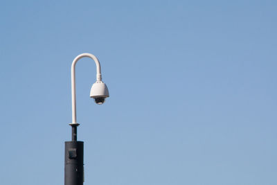 Low angle view of security camera against clear blue sky