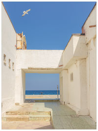 Building by sea against clear blue sky