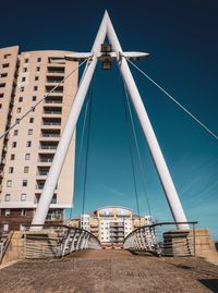 Low angle view of bridge and buildings against clear blue sky