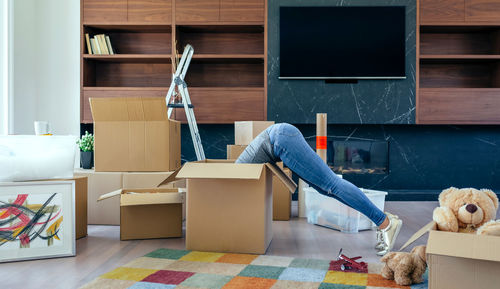 Low section of woman in cardboard box at home