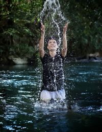 Young man splashing water in waterfall