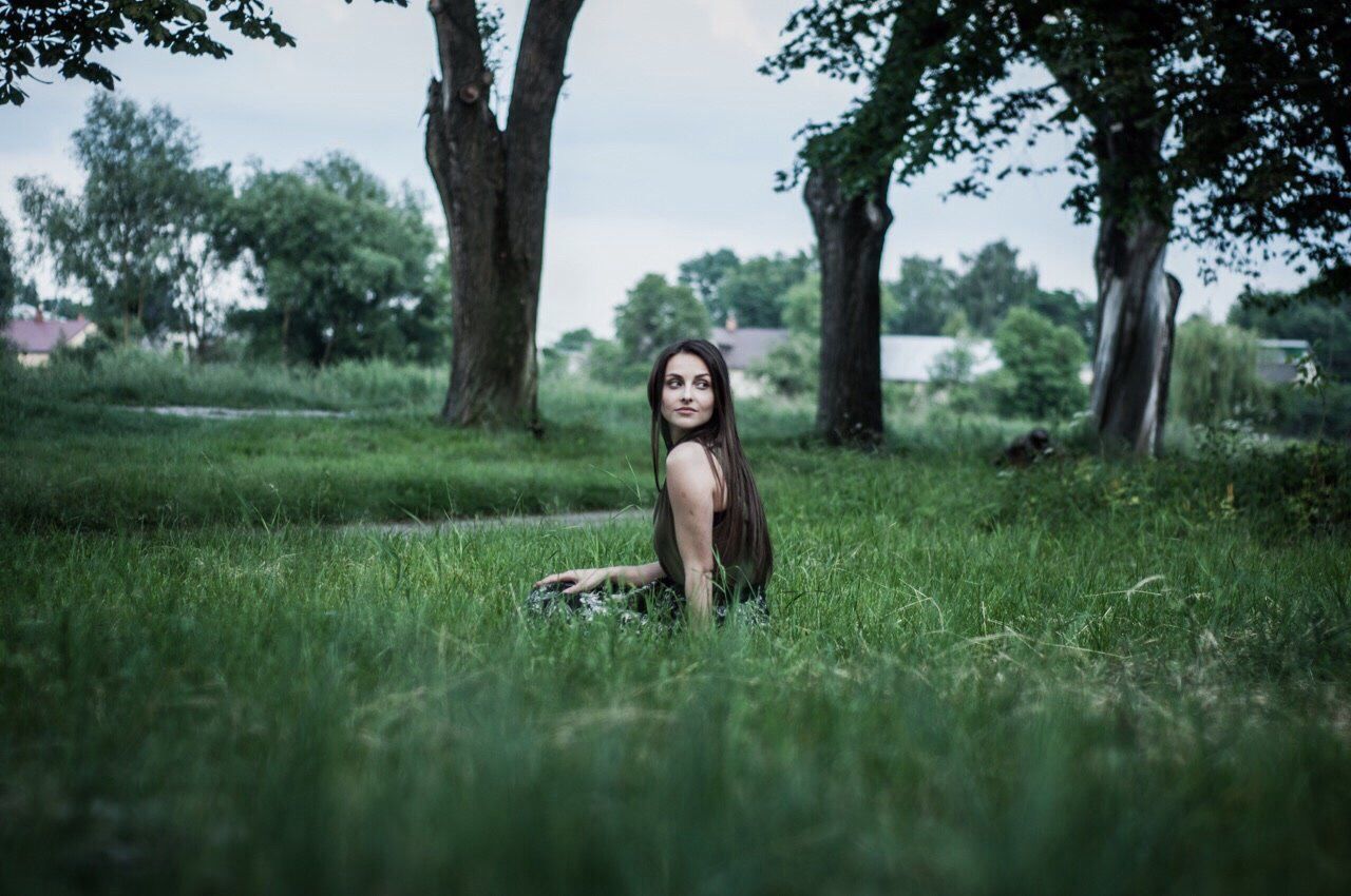 PORTRAIT OF WOMAN SITTING ON FIELD