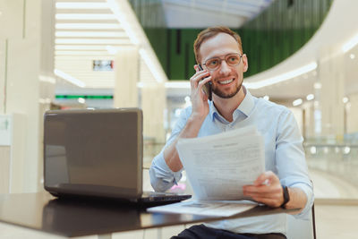 Young woman using mobile phone while sitting at office