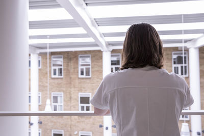 Rear view of female doctor standing by railing in hospital