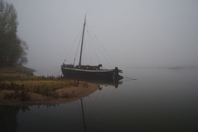 Sailboats moored in lake against sky