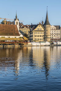 Luzern is reflected on the river on a sunny day with the chapel bridge