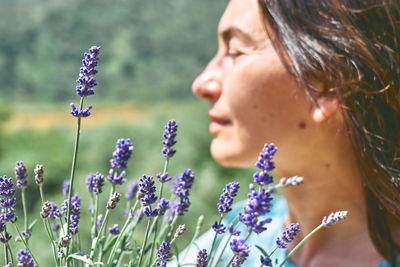 Defocused happy face of woman behind blooming scented organic lavender flowers