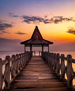 Surface level of pier against sky at sunset