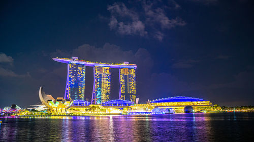 Illuminated bridge over river against sky at night