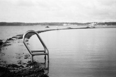 Metal railing on beach against sky