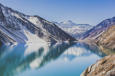 Scenic view of lake and mountains against clear blue sky