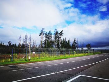 Road by trees against sky