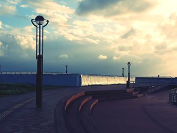 Walkway by sea against sky during sunset