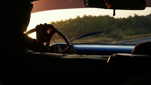 Silhouette person driving car during sunset