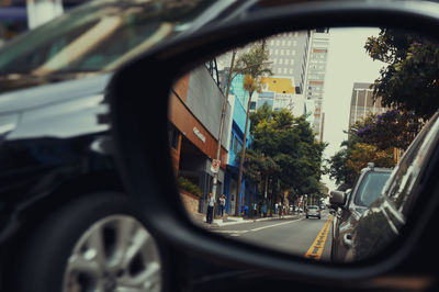 Road seen through side-view mirror of car