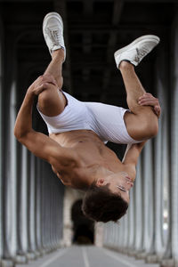 Full length of shirtless young man jumping below bridge