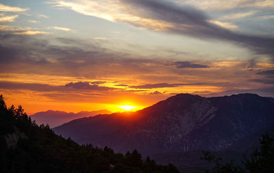 Scenic view of silhouette mountains against orange sky