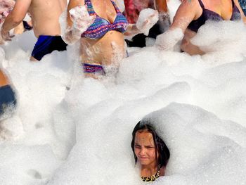 People amidst soap sud at water park