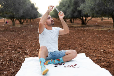 Rear view of woman drinking water while sitting on field