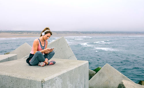 Woman sitting on pier against sky