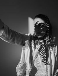 Portrait of young woman standing against gray background