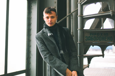 Portrait of young man standing in window