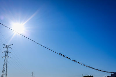 Low angle view of power lines against clear blue sky