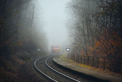 Railway during autumn weather. passenger train leaving railroad station in foggy forest.