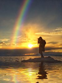 Man standing on beach against sky during sunset