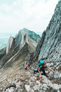 Two young women climbing steep rock couloir in swiss alps