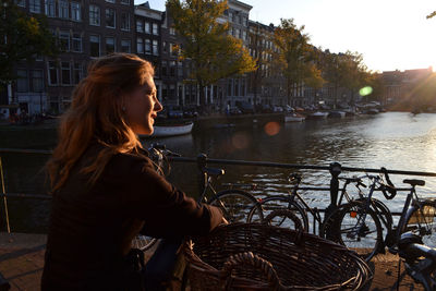 Side view of woman against river at sunset