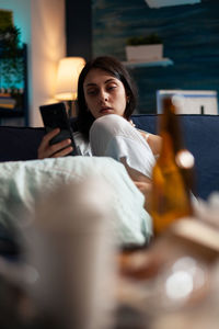 Portrait of young woman sitting on bed at home