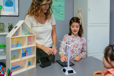 Student showing solar windmill to classmate in ecology classroom